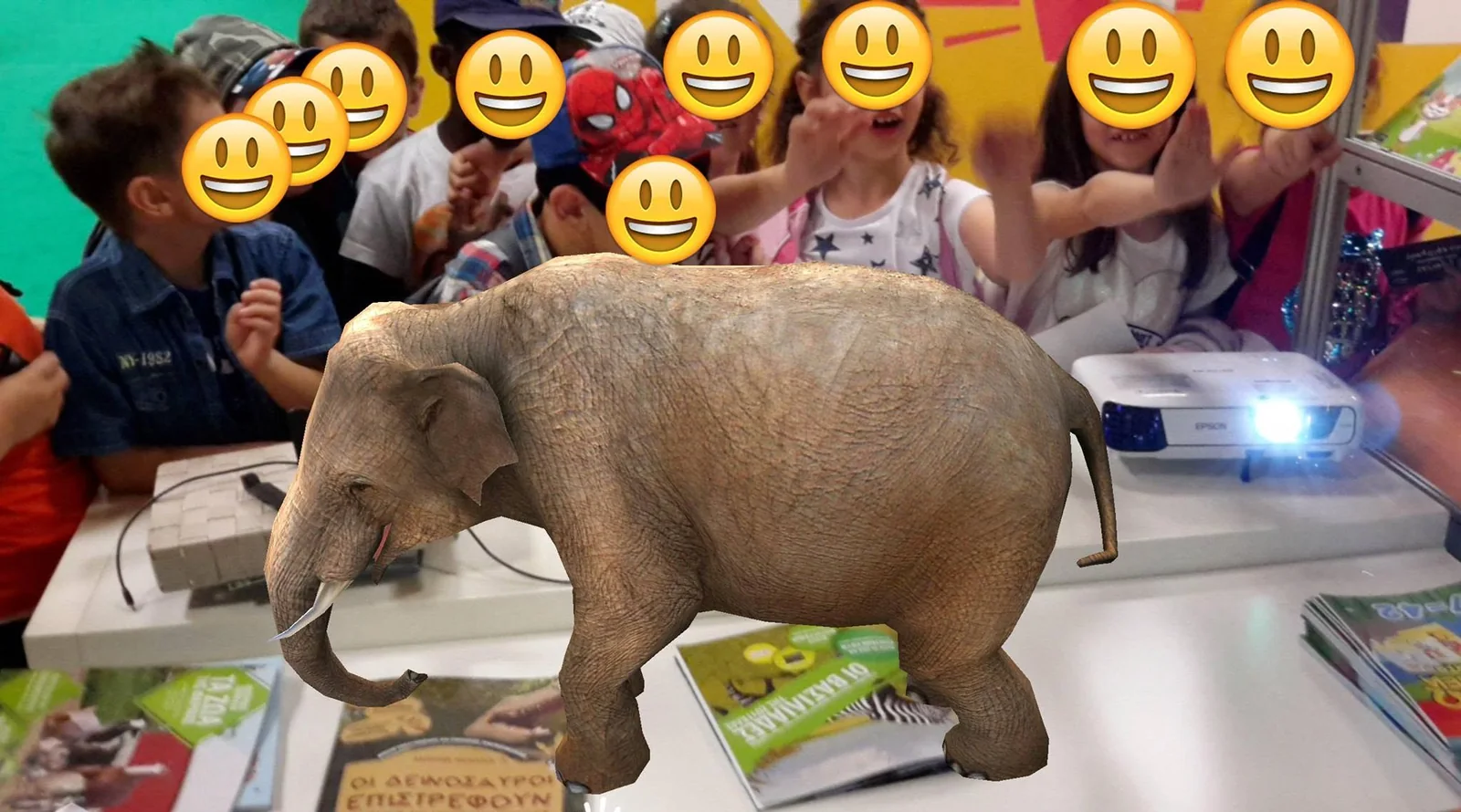 Children crowding around a table at a book fair while a 3D elephant stands on the books