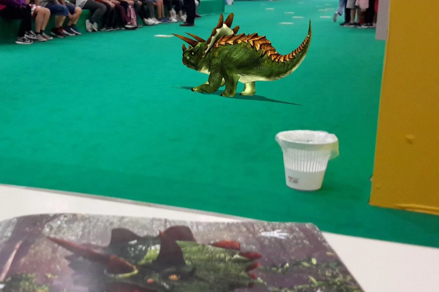 A 3D stegosaurus on the carpet of a book fair, next to the open book